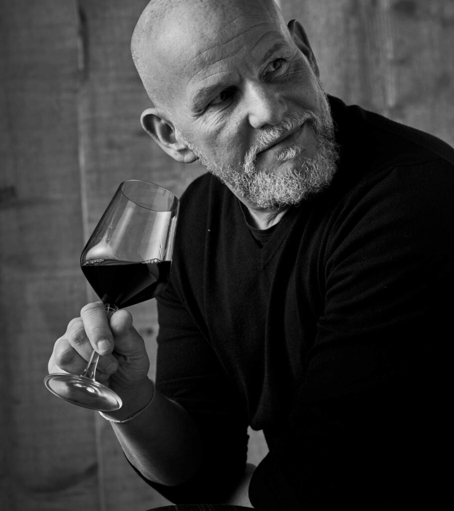 Portrait of Massimo Lentsch holding a glass of wine.