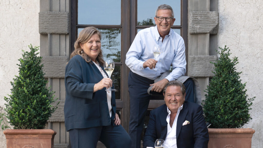 Three Berlucchi brothers holding glasses of Franciacorta, celebrating tradition and elegance.